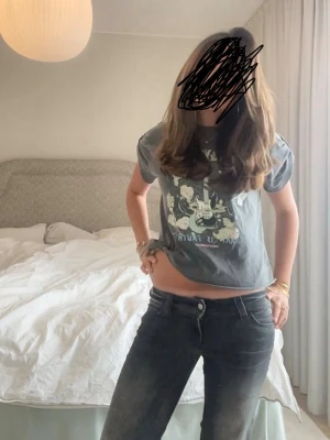 Grå Zadig & Voltaire t-shirt med tryck - Snygg grå t-shirt från Zadig & Voltaire med coolt tryck av elgitarr och blommor på framsidan. T-shirten har korta ärmar och en normal passform. Perfekt för dig som vill ha en unik och trendig look. Storlek står ej pga lappen är avklippt men passar från xs-s skulle jag säga 