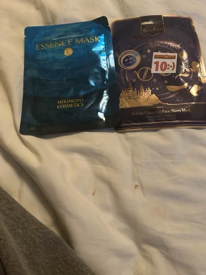 Ansiktsmasker Mikimoto & Harry Potter - Två ansiktsmasker: en blå Essence Mask från Mikimoto Cosmetics och en Harry Potter Colour Changing Face Sheet Mask med bärdoft. Båda är engångsmasker i förpackning, perfekta för en återfuktande och rolig self-care stund.