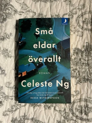 Små eldar överallt av Celeste Ng - En roman av Celeste Ng med omslag i blå och gröna toner som visar ett villakvarter på natten. Boken är i pocketformat och utgiven av Månpocket. Handlingen kretsar kring familjer och hemligheter i Shaker Heights. Perfekt för dig som gillar gripande berättelser.