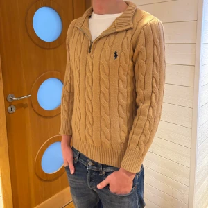Polo Ralph Lauren tröja  - Kabelstickad beige tröja från Polo Ralph Lauren med halv dragkedja och hög krage. Tröjan är i väldigt bra skick utan några defekter. Tröjan är i storlek M men passar S. Modellen är 180cm lång och väger 68kg. Hör av er vid frågor (pris kan diskuteras).