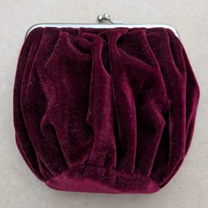 Vinröd sammet kuvertväska - HELT OANVÄND kuvertväska. Elegant vinröd kuvertväska i mjuk sammet med en klassisk metallram och knäppe. Perfekt för att ge en lyxig touch till din outfit.