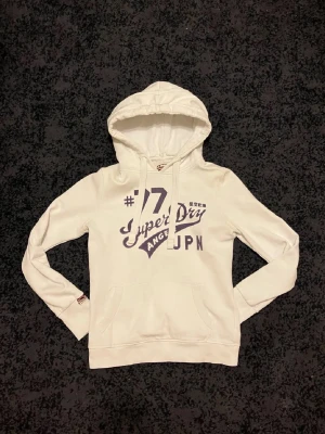 Superdry hoodie - Skön vit superdry hoodie. Har knappast andvänt och sitter lite tigthare i form. Litet defekt på axeln men är svårt att märka. Tar också byten om intresse. Kom med bud! 