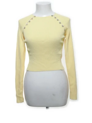 Ribbad tröja med knappar - Snygg ljusgul långärmad tröja med tight passform och dekorativa knappar längs axlarna. Tröjan har rund halsringning och är ribbstickad för en bekväm känsla. Perfekt för dig som gillar stilrena detaljer och en fräsch look.