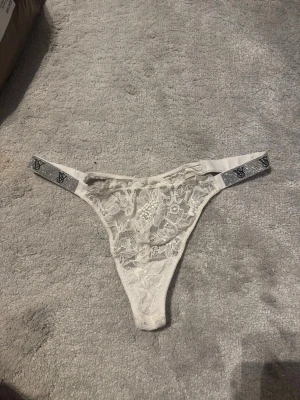 🩶 Vit spets-string med strassdetaljer - Vit stringtrosa i spets med dekorativa strassdetaljer på sidorna. Elegant och feminin modell som sitter fint på kroppen.