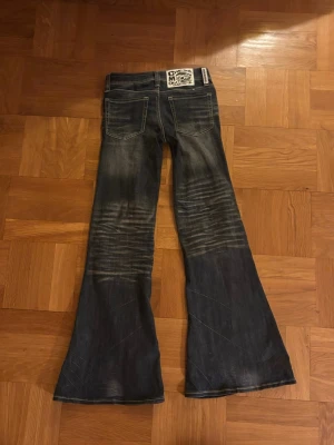 Mörkblå low waisted flared jeans från Cheap Monday - Säljer ett par mörkblå bootcut jeans med snygga detaljer. Storlek 32 och aldrig använda.