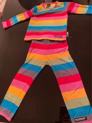 Randigt set från Villervalla storlek 86 - Färgglatt tvådelat set från Villervalla med långärmad tröja och byxor. Setet har breda ränder i rosa, rött, gult, blått och grönt. Mjukt och stretchigt material, perfekt för chill dagar eller som mysplagg.