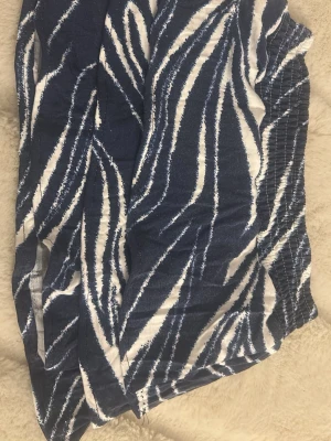 Blåvita shorts med zebramönster - Snygg volangkjol i blått och vitt med zebramönster och elastisk midja. Perfekta för sommardagar och har en loose passform som ger en avslappnad vibe. Materialet känns lätt och luftigt, perfekt för varma dagar. 