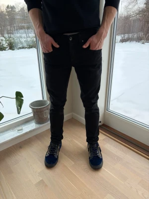 Svarta skinny jeans från tiger of sweden - Svarta jeans från Levis i skinny fit med klassisk femficksdesign och knappgylf. Snygg, smal passform som sitter tajt längs benen. Perfekta för dig som gillar en stilren och modern look.