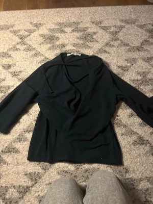 Mörkgrön omlottkofta från Filippa K - Stilren mörkgrön omlottkofta från lager 157 med knytband i midjan och långa ärmar. Perfekt för lager på lager och enkel att matcha med olika outfits. Mjuk och skön kvalitet som ger en avslappnad men ändå snygg look.