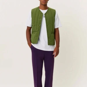 Grön quiltad väst från Les Deux - Stilren grön quiltad väst från Les Deux med raka linjer och tryckknappar framtill. Västen har två fickor och är tillverkad i ett lätt syntetmaterial. Använd endast ett par gånger.