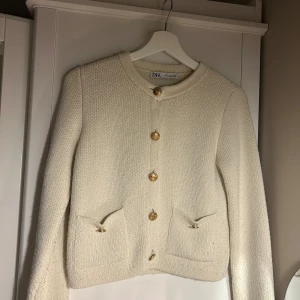Beige stickad kofta från Zara - Superfin beige stickad kofta från Zara med guldknappar framtill och två fickor. perfekt att slänga över en topp för en chic look. Klassisk och enkel modell som passar till allt. Den är använd många gånger 💕