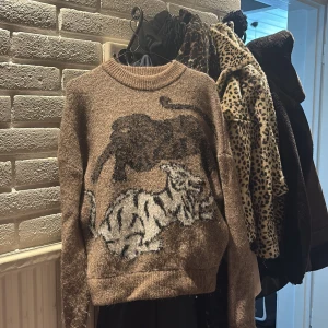 Brun stickad tröja med tigrar - Cool brun stickad tröja med två stora tigrar i svart och vitt på framsidan. Väldigt mysig tröja inför hösten🍂🍁🤎🤎