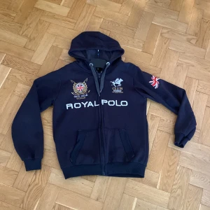 Zip-Hoodie Geographical Norway - Säljer min zip-hoodie från Geographical Norway. Tröjan är mörkblå med många feta detaljer, en tröja som får dig att sticka ut med en stilren look. Över bröstet står det Royal Polo. Skön tröja som passar nu till kallare väder. 