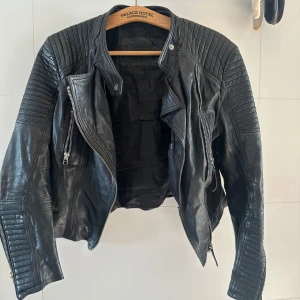 Svart skinnjacka PrimeBoots - Snygg svart skinnjacka från PrimeBoots med coola quiltade detaljer på axlar och ärmar. Jackan har dragkedjor framtill och vid ärmslut. Tyvärr har sömmen gått sönder inuti jackan, de går nog att laga. Inget som syns dock när man har på sig den. Äkta skinn.