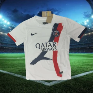 PSG vit matchtröja Nike Qatar Airways - Snygg vit fotbollströja från Paris Saint-Germain med Nike-logga och Qatar Airways-tryck. Tröjan har korta ärmar med röda och mörkblå detaljer samt ett unikt penseldragsmönster i rött och mörkblått framtill. Perfekt för dig som älskar PSG och vill sticka ut på planen.