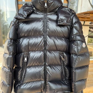 Moncler Maire storlek 4 Dam - Säljer en svart pufferjacka från Moncler med glansig finish, hög krage och avtagbar huva. Jackan har dragkedja framtill, två fickor med dragkedja och en ärmficka med Moncler-logga. Perfekt för kalla dagar och riktigt snygg streetstil. Mycket bra skick knappt använd! Kostar 18.000kr Ny 