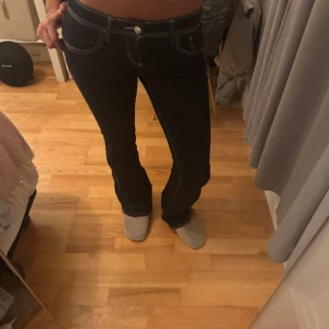 Mörkblå bootcut jeans från Gina Tricot - Säljer ett par mörkblå bootcut jeans från Gina Tricot, modell Perfect Jeans. Jeansen har låg midja, tydliga vita sömmar och klassisk femficksdesign. Materialet är stretchigt jeans och passformen är normal. Perfekta för dig som gillar en snygg siluett med lite utsvängda ben.