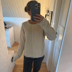 Vit stickad tröja från Zara - Säljer en vit stickad tröja från Zara i storlek L Tröjan har en enkel design med en dekorativ söm framtill, rund hals och ribbade muddar vid ärmslut och nederkant. 