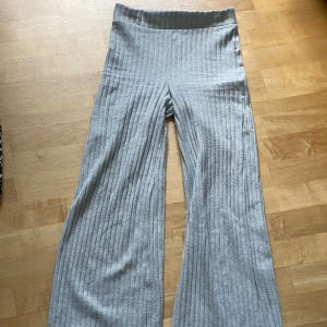 Grå ribbade vida byxor - Säljer ett par grå supersköna mjukisbyxor som är i ett ribbat material med hög midja och bootcut i benen. Använda men i fint skick!🤩Minns inte riktigt vart dom är ifrån då lappen är borta , men skulle säga att de passar xs/s☺️