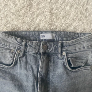 Ljusgrå jeans med slits från Zara - Säljer ett par ljusgrå jeans från Zara. Jeansen är raka med slits och är i väldigt bra skick. Säljer då de inte längre kommer till användning.(skriv för fler bilder)