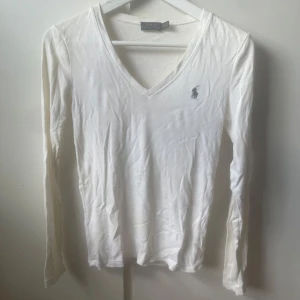 Vit långärmad tröja Polo Ralph Lauren - Vit långärmad tröja från Polo Ralph Lauren i mjuk bomull. Tröjan har v-ringning och den klassiska broderade loggan på bröstet. Enkel och stilren som passar till allt! 