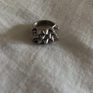 Edblad ring - Cool bred Edblad ring i silverfärg med flera rader av spetsiga nitar runt hela ringen. Ger en edgy och unik look, perfekt för dig som gillar statement-smycken. Ringen är i metall och har en riktigt tuff design som sticker ut.