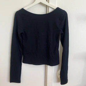 Svart långärmad topp från Gina Tricot - En svart långärmad topp från Gina Tricot med rundad, något djupare halsringning. Modellen är figurnära och enkel, perfekt att styla med jeans eller kjol. Tillverkad i mjuk bomull som känns skön mot huden.