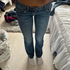 Blå bootcut jeans från Guess - Snygga blå jeans från Guess med bootcut passform och låg midja. Jeansen har klassiska fem fickor, orangea kontrastsömmar och broderad detalj på bakfickan. Tillverkade i stretchig denim för extra komfort. Köpte de på Vinted och har gammal ägares bilder pga av att de inte passar mig💕pris kan diskuteras