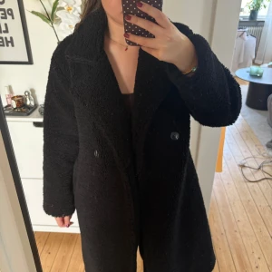 Svart teddyjacka med knappar - Superfin fluffig teddyjacka i en längre modell från Bikbok. I fint skick men har tyvärr gått upp i sömnen på insidan vid ärmen. Det är ingenting man känner av men man kan se att den är sönder där om man tittar på insidan. Detta går såklart lätt att fixa genom att sy om man vill det🥰 (Se bild för att se defekten). Storlek XS men passar mig som är S vanligtvis då den är lite större i modellen. Köpt för 999kr ❤️