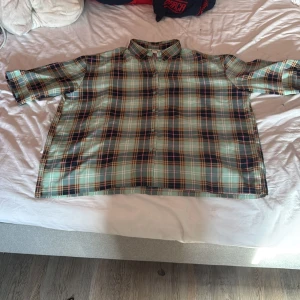 Rutig skjorta från Monki i mint och navy - Säljer en oversized rutig skjorta från Monki i mintgrönt, marinblått, brunt och rosa. Skjortan har klassisk krage, knappar framtill och trekvartsärmar. Perfekt för en chill och trendig look.