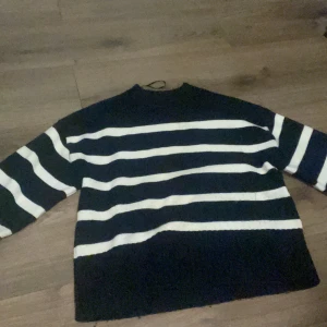 Randig stickad tröja i marinblått och vitt - Säljer en stickad tröja med breda marinblå och vita ränder. Tröjan har lång ärm, ribbade muddar och en avslappnad passform. Perfekt för dig som gillar klassisk stil med en modern twist.