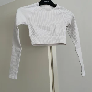 Vit ribbad croppad topp från Aimn - Säljer en vit croppad långärmad topp från Aimn. Toppen är ribbad. Materialet är mjukt och stretchigt, vilket gör den bekväm att bära.