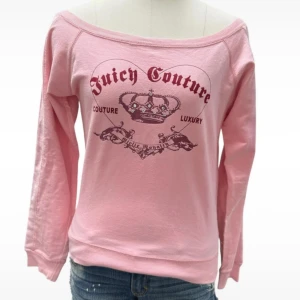 Rosa offshoulder tröja Juicy Couture - Säljer en rosa långärmad tröja från Juicy Couture med offshoulder-skärning och tryck med krona och text framtill. Tröjan är i mjuk bomull och har en avslappnad passform, perfekt för en chill och trendig look.