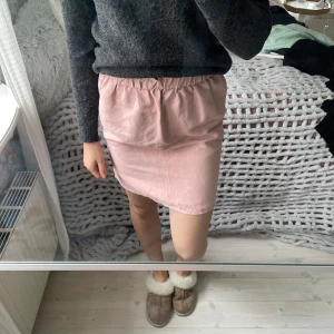 Rosa kjol i mockaimitation  - Ljusrosa kjol från H&M med resår i midjan och lätt rynkad kant upptill. Kjolen är i mockaimitation och lite längre i modellen men går att vika ner. 