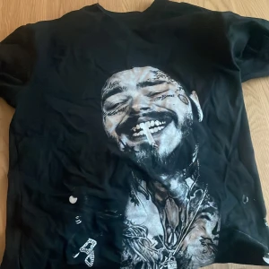 Svart t-shirt med tryck från Hennissy - Svart t-shirt från Hennissy Aesthetics i storlek S. Framsidan har ett stort grafiskt tryck med detaljer i vitt och grått, samt coola motiv och smyckesdetaljer. Klassisk rund hals och korta ärmar. Materialet känns som mjuk bomull.