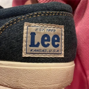 Lee denim slip-on sneakers - Säljer ett par coola slip-on sneakers från Lee i mörkblå denim. Skorna har en vit platt sula och ett Lee-märke på hälen. Perfekt för dig som gillar streetstyle och unik look.