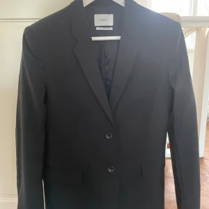 Svart ullkavaj från Filippa K, Small - Klassisk svart ullkavaj från Filippa K i storlek Small. Klassisk modell med två knappar framtill, smala slag och fickor med lock. 