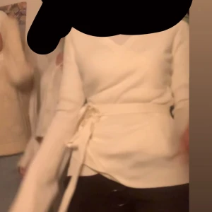 Vit omlottopp från köpt från Zalando - Säljer en vit omlottopp från Urban Classics i ribbad polyester. Toppen har långa ärmar, v-ringning och knytband i midjan som ger en snygg siluett. Perfekt för dig som gillar stilrena och trendiga plagg med lite extra detalj. Fråga om du vill ha fler bilder! Använt ett par gånger, köpte för ungefär 600kr