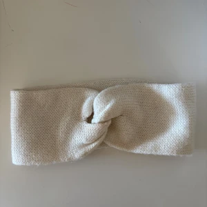 Stickat vitt diadem med twist - Snyggt stickat diadem i vitt med twistad detalj framtill. Perfekt accessoar för att hålla håret på plats och ge en mysig touch till din look. Mjukt material som sitter bekvämt runt huvudet.