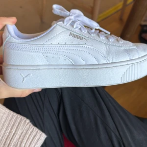 Vita sneakers från Puma med platåsula - Säljer ett par fräscha vita sneakers från Puma med snygg platåsula. Skorna har klassisk snörning, rund tå och är tillverkade i skinnliknande material. Nypris = 700. Har aldrig använts 
