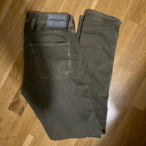 Replay Anbass grå jeans slim fit 29/32 - Säljer ett par Replay Anbass jeans i grå färg med klassisk femficksdesign och snygga detaljer på bakfickorna. Jeansen har slim passform och är tillverkade i mjuk bomullsblandning med lite stretch för extra komfort. Perfekta för dig som gillar stilrena och moderna jeans. Grå/khaki.