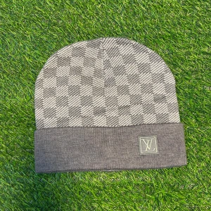 Grå rutig L-V mössa - Snygg grå mössa från L-V  med klassiskt rutigt mönster och vikt kant. L-V logga framtill i broderad patch. Tillverkad i mjukt stickat material som håller dig varm och stilren under kalla dagar.