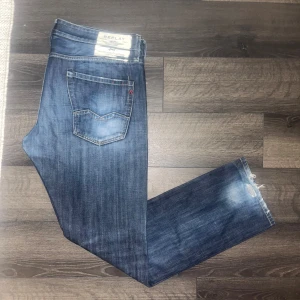 Replay  jeans  - Säljer ett par blå jeans från Replay med klassisk femficksdesign och snygga slitningar vid bensluten. Jeansen har raka ben och normal passform, tillverkade i slitstarkt denimtyg. Bra skick förutom defekten som syns vid bensluten. Midja 51cm, längd 109cm. JAG SKICKAR INGA FLER BILDER NÄR JAG BÄR JEANSEN :) (12)