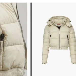 Beige croppad pufferjacka med huva - Snygg croppad pufferjacka i beige med huva och dragkedja framtill. Jackan har quiltad design och ribbad nederkant för extra stilpoäng. Perfekt för dig som vill ha en trendig och varm look under kyliga dagar.