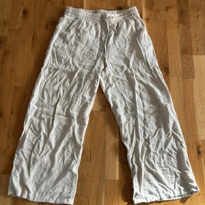 Beiga linnebyxor från JDY  - Luftiga beiga linnebyxor från JDY med elastisk midja och snörning. Byxorna har raka, vida ben. 