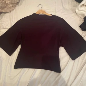 Svart topp öppen i ryggen - Säljer denna svarta toppen från Gina Tricot med halvt öppen rygg som man kan knyta en rosett där bak