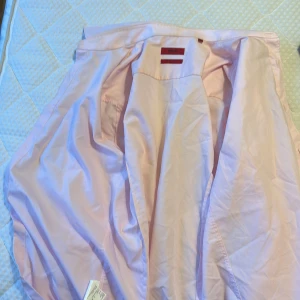 Ljusrosa skjorta Hugo Boss  - Snygg ljusrosa skjorta från Hugo Boss med extra slim fit och klassisk krage. Skjortan har knappar framtill och är långärmad. Materialet är mjuk bomull som är lätt att stryka. Perfekt för dig som gillar stilrena och moderna plagg med en fräsch vibe.