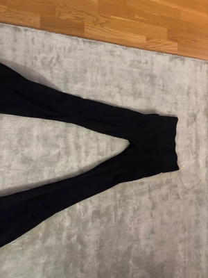 Svarta ribbade leggings med hög midja - Svarta leggings med ribbad struktur och hög midja. De har en tight passform och är perfekta för en trendig och bekväm stil. Passar till många olika outfits och är lätta att matcha.