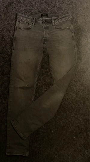 Grå skinny jeans från Jack & Jones - Säljer ett par grå slim fit  jeans från Jack & Jones. Jeansen har klassisk femficksdesign, smal passform och är tillverkade i stretchig denim för extra komfort. Perfekta för dig som gillar en modern och stilren look.