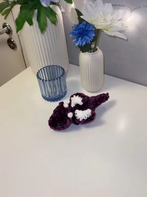 Lila bäbisdrake med vita detaljer💜🤍 - Denna urgulliga bäbisdrake vill hitta sitt nya hem🐉🐲Den har hårda genomskinliga ögon🤍💜 Den är ungefär likas stor som min handflata🐉 så cirka 15cm långa🐲 Vikrad med massa kärlek, med mjukt garn från Rusta💜💜